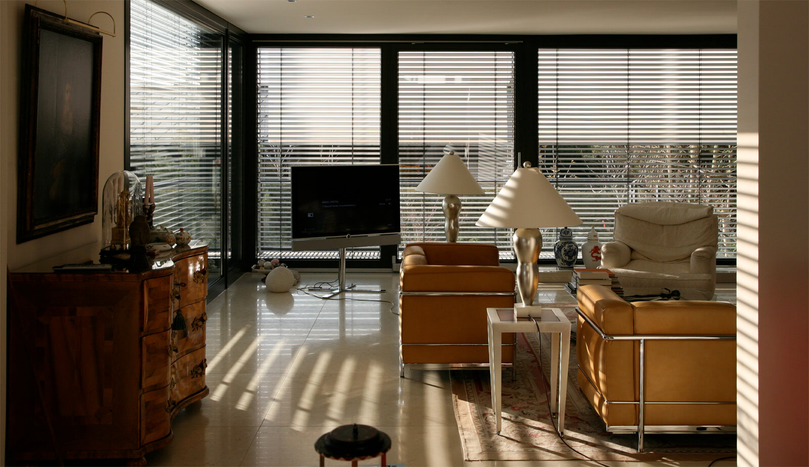 Doppelvilla: Wohnraum mit Ledersesseln, Kommode und Jalousien vor Glasfront