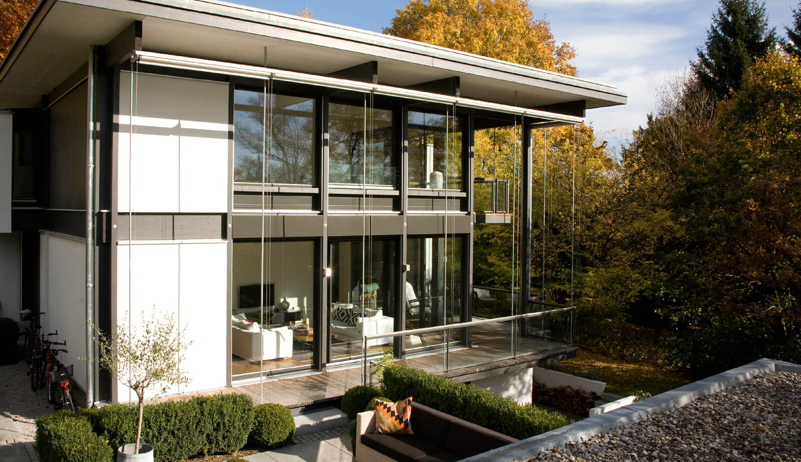 Flachdach-Kubus: verglaste Gartenfassade mit Balkon im Herbstlicht