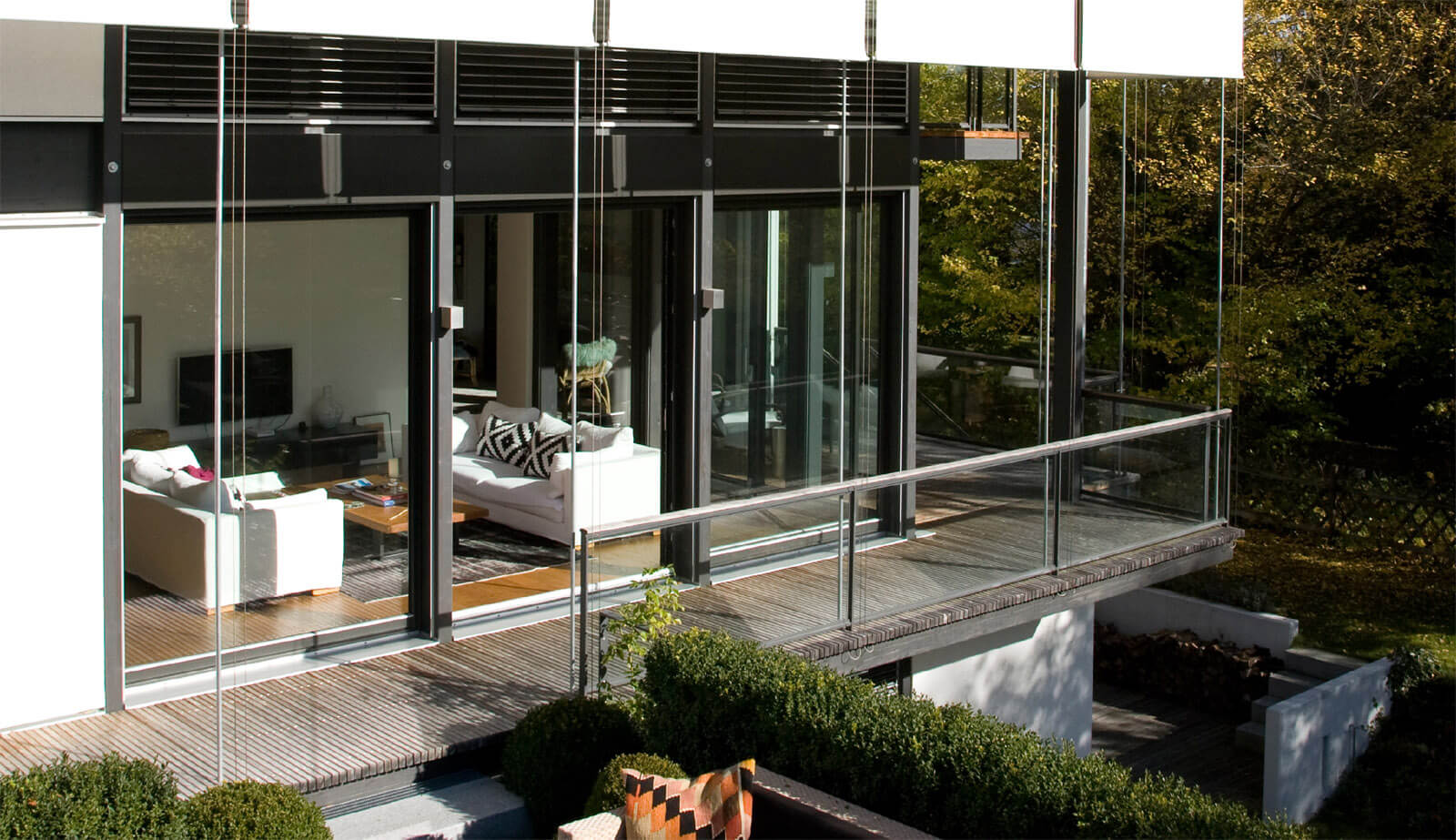 Flachdach-Kubus: Balkon mit Glasgeländer vor dem verglasten Wohnraum