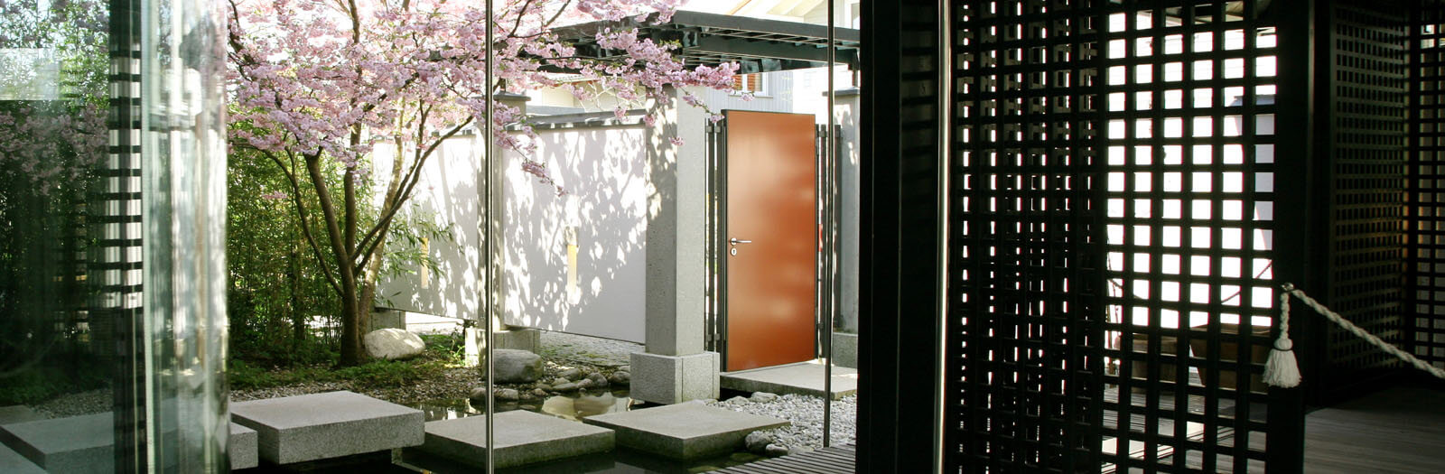 Haus am See: Eingangshof mit Trittsteinen, Kirschblüte und roter Tür