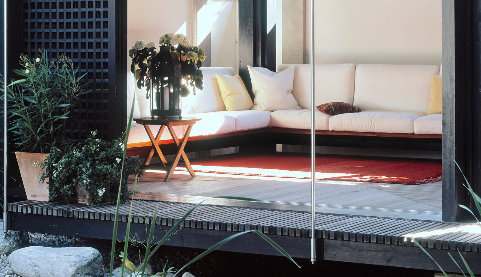 Haus am See: Sitzecke mit weißen Polstern und rotem Teppich im Pavillon