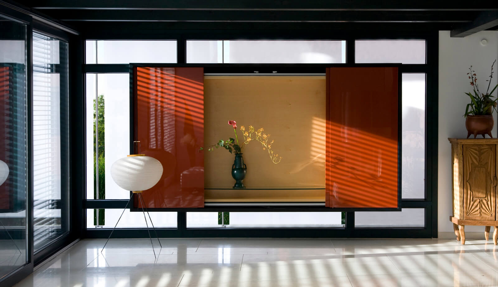 Haus am See: rote Vitrine mit Blumenvase vor dem Fenster