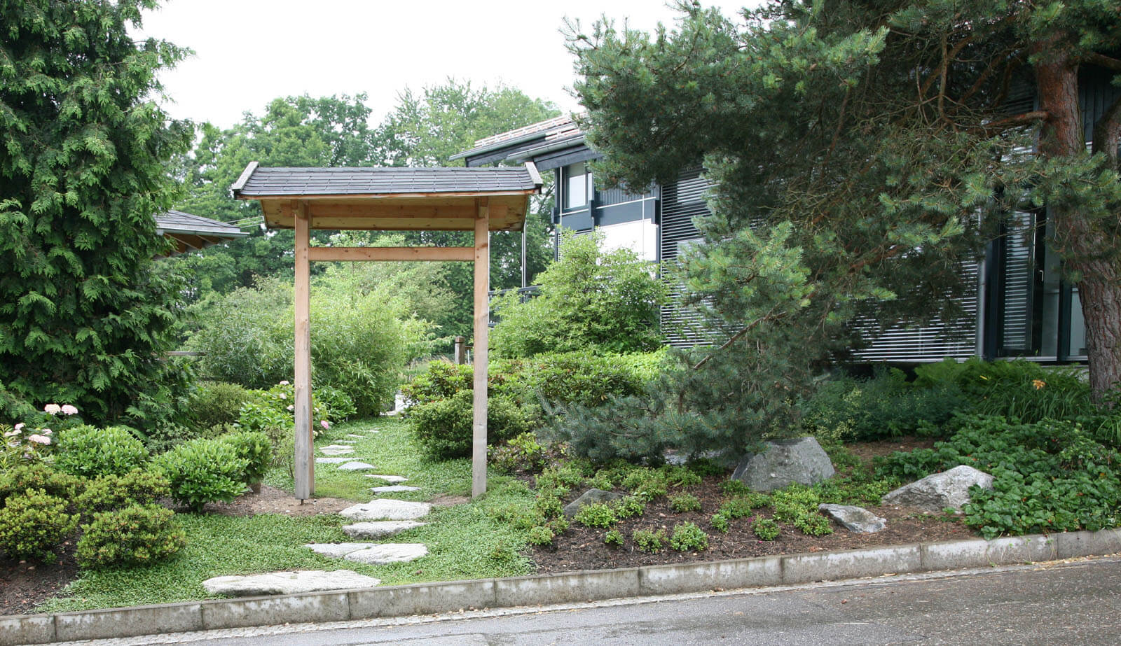 In der Baumschule: Holztor und Trittsteinweg durch den Garten zum Haus