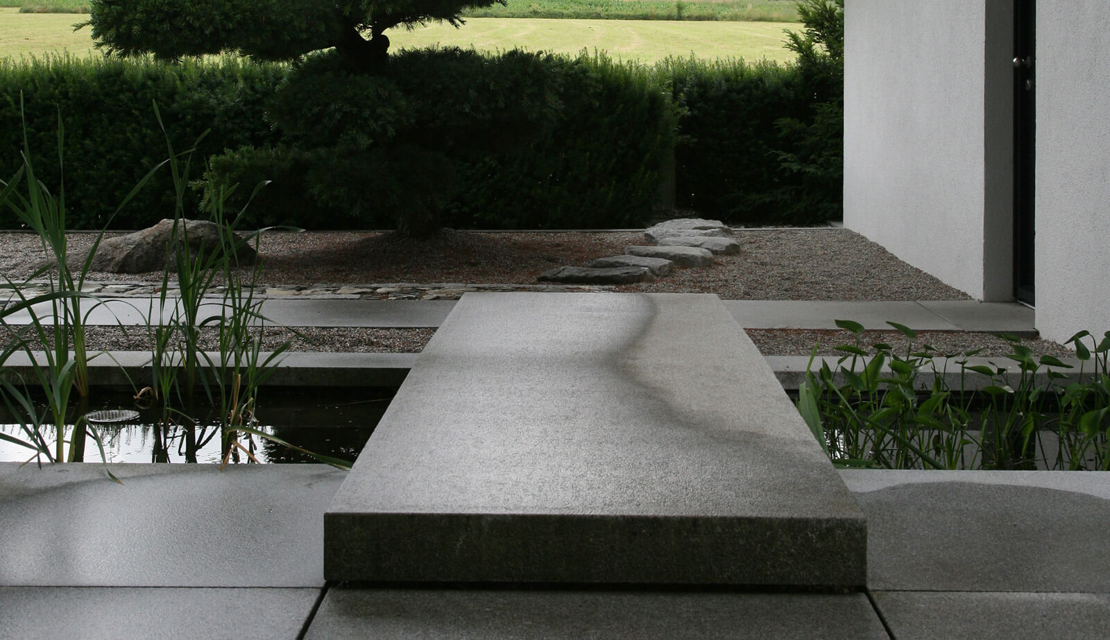 In der Baumschule: Steinplatte über Wasserbecken mit Blick in den Kiesgarten