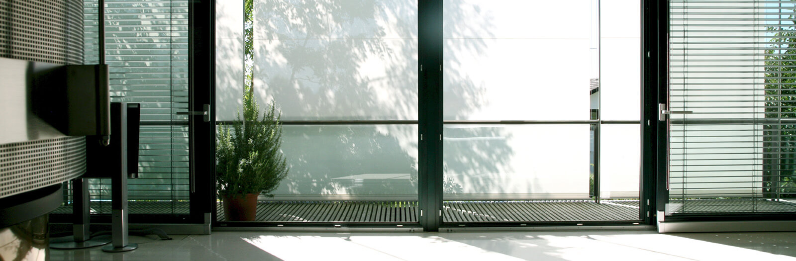 Haus in Hanglage: heller Wohnraum mit Glasfront und Jalousien