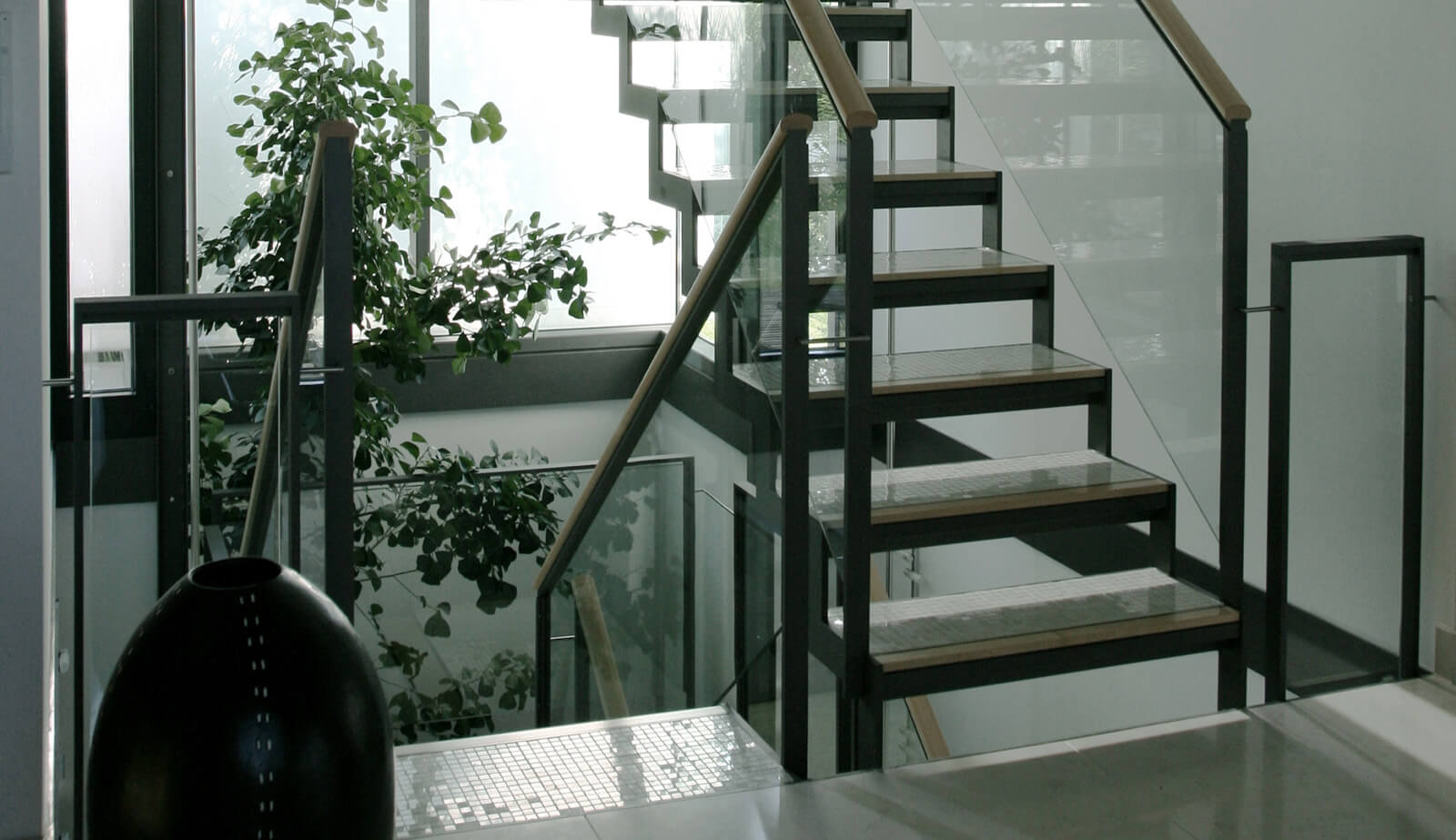 Haus in Hanglage: offene Stahltreppe mit Glasgeländer und Pflanzen
