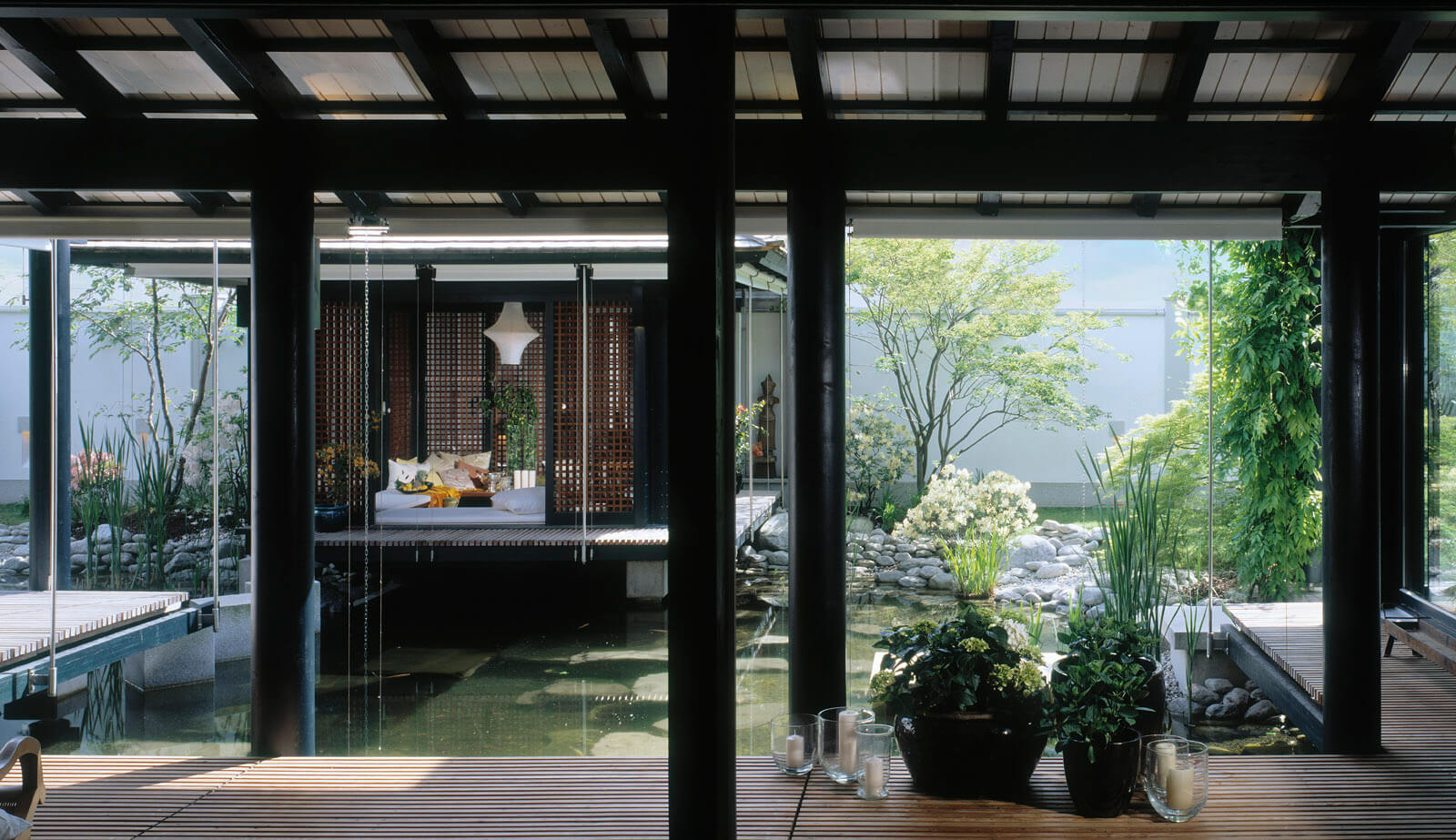 Haus mit Höfen: überdachte Holzterrasse mit Blick über Teich zum Pavillon