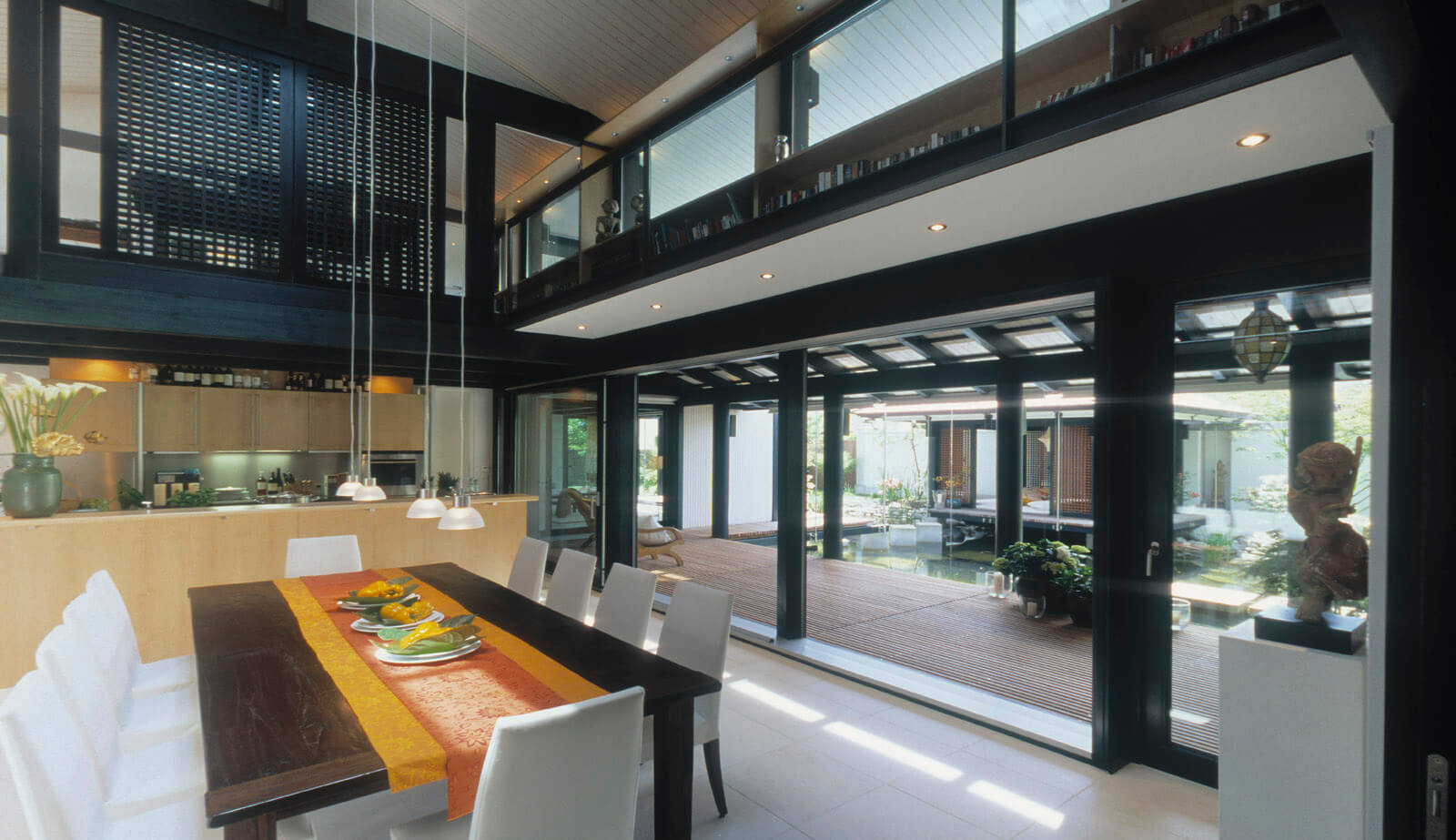 Haus mit Höfen: Esstisch und Küche im zweigeschossigen Wohnraum