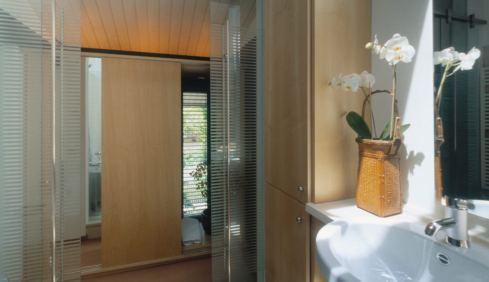 Haus mit Höfen: Bad mit Waschbecken, Orchideen und Holzschiebetür