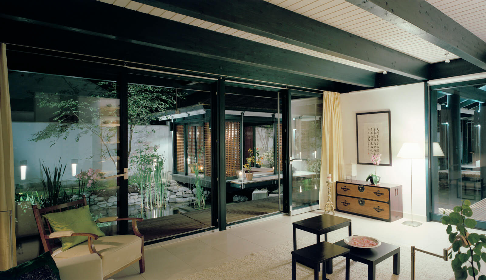 Haus mit Höfen: Wohnraum mit Sessel und Kommode, Blick auf den Teich