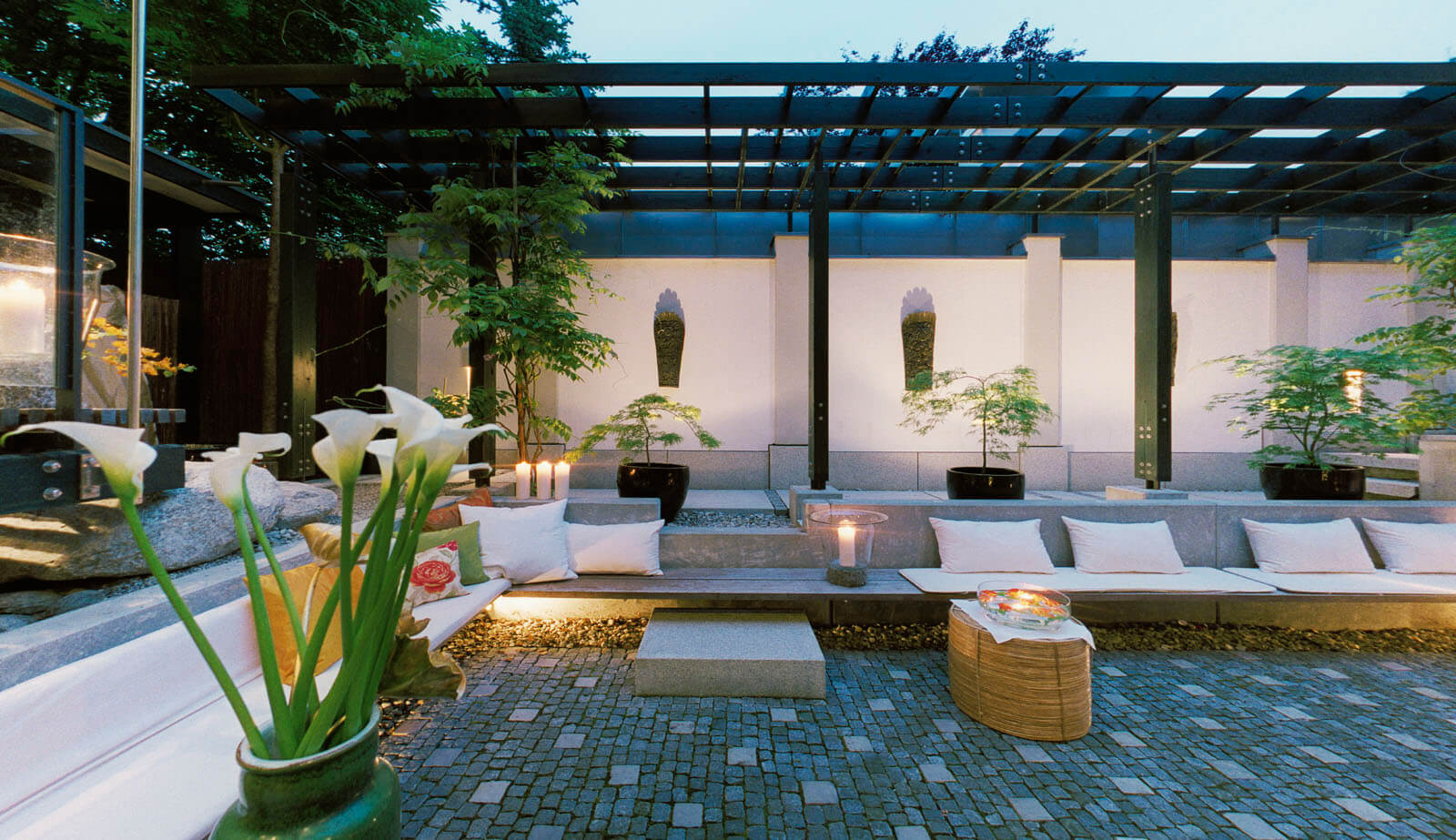 Haus mit Höfen: Hof mit Pergola, Sitzbank und Calla in der Abenddämmerung