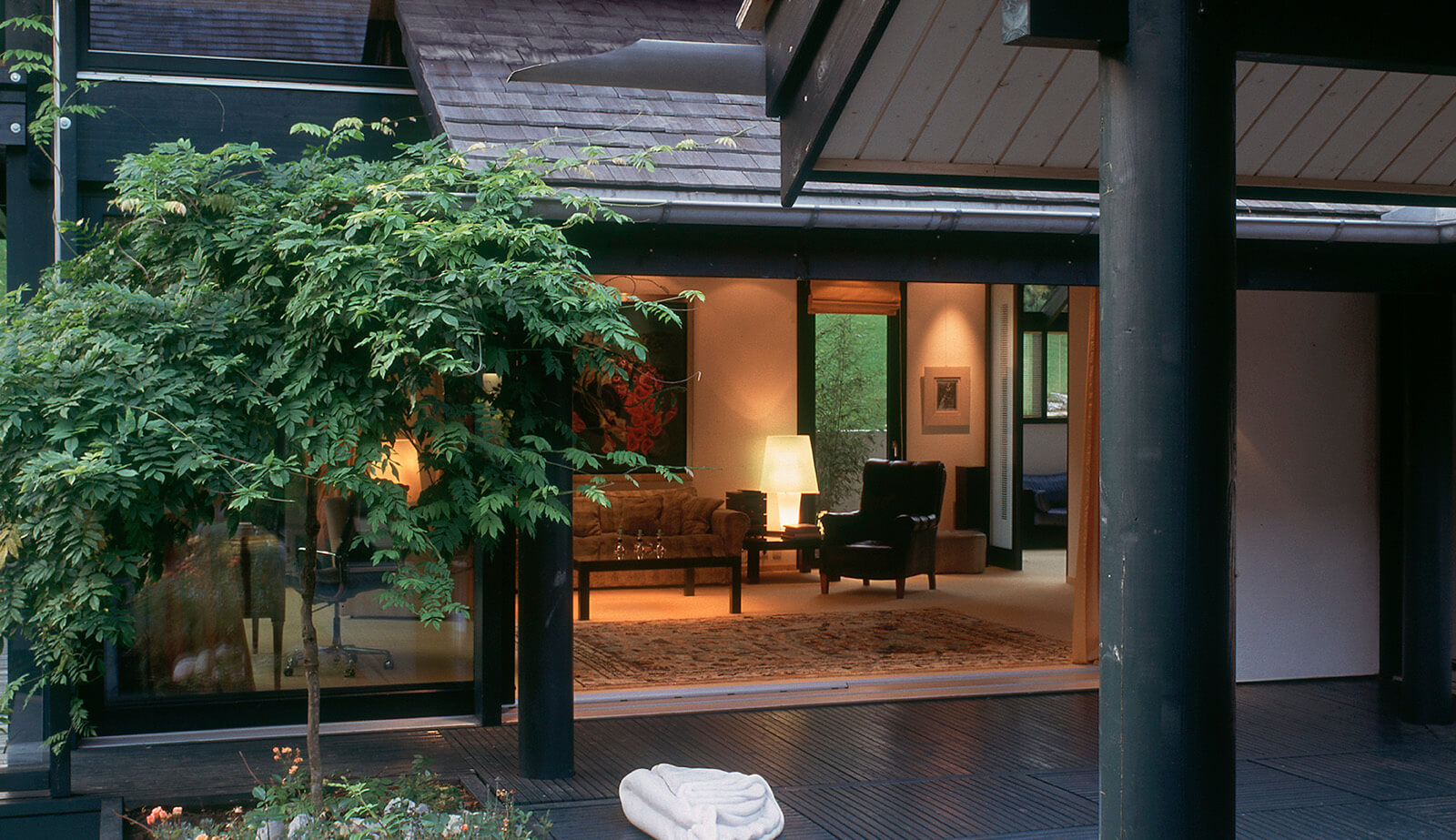Villa im Park: Blick über die Terrasse in den beleuchteten Wohnraum