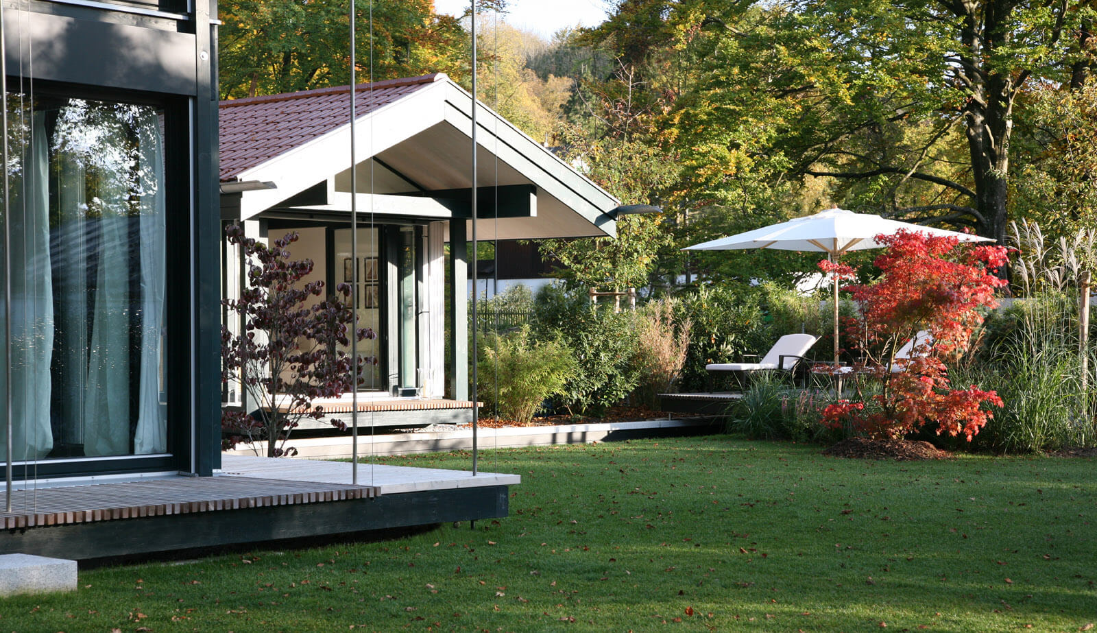 Haus mit Gästehaus: Gästehaus mit Satteldach, Sonnenschirm und Ahorn im Herbst
