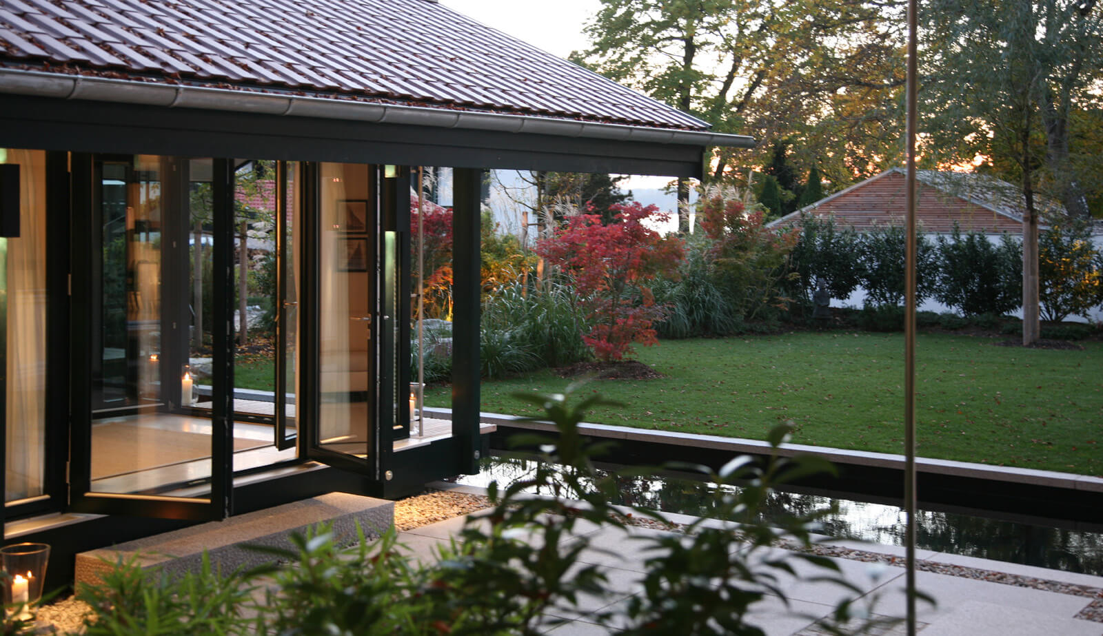Haus mit Gästehaus: verglaster Pavillon mit Ziegeldach am Wasserbecken