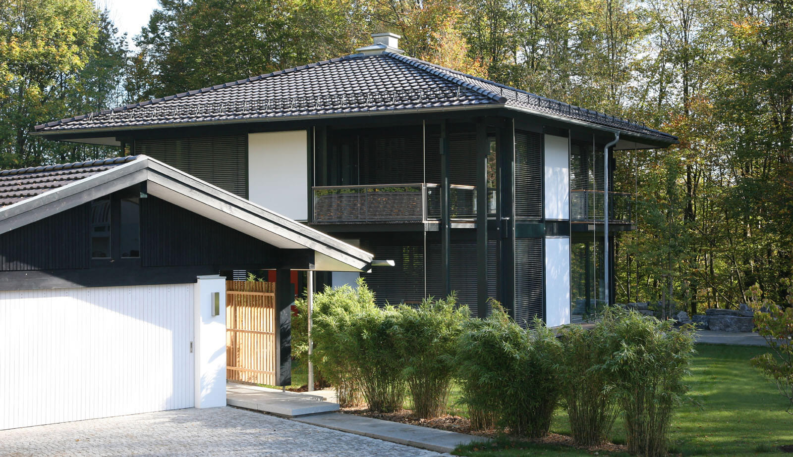 Zeltdachvilla: Zeltdachhaus mit Balkon hinter Garage und Bambus