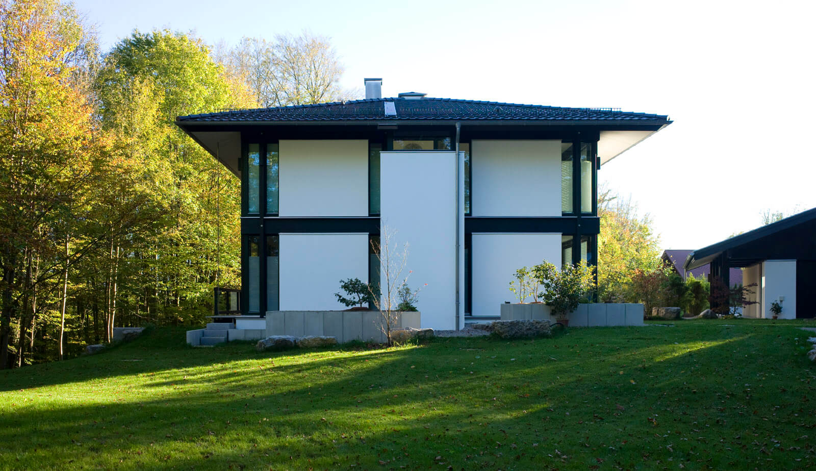 Zeltdachvilla: weiße Fassade mit dunklem Fachwerk über großer Rasenfläche