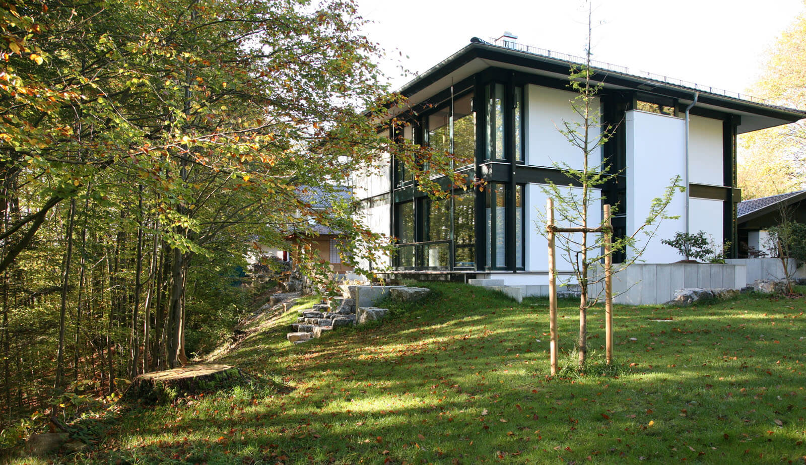 Zeltdachvilla: Hangseite mit Natursteintreppe zwischen herbstlichen Bäumen