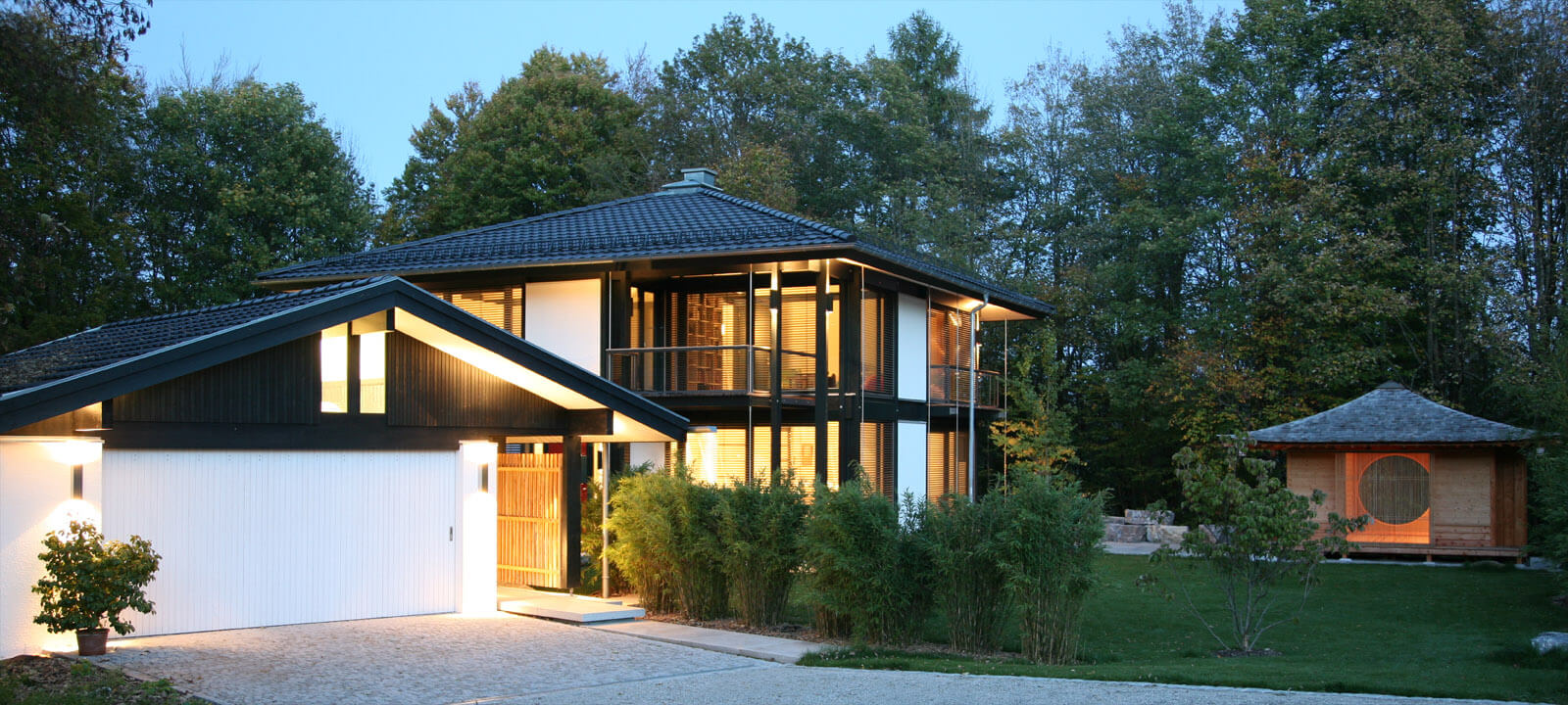 Zeltdachvilla in der Abenddämmerung mit Garage, Eingang und Teepavillon