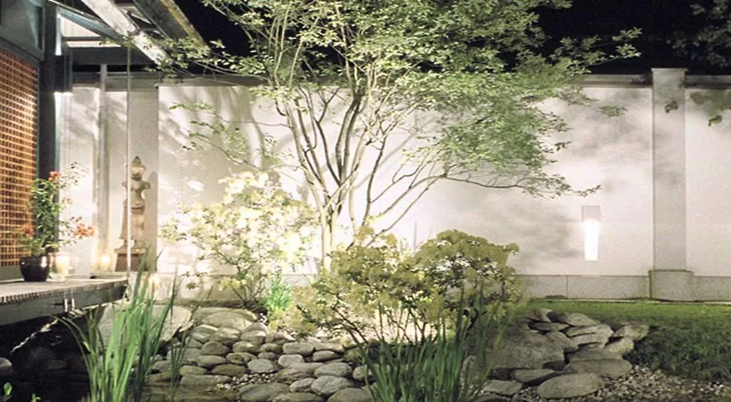 Haus mit Höfen: Bepflanzung und Kiesel am Koi-Teich vor weißer Gartenmauer