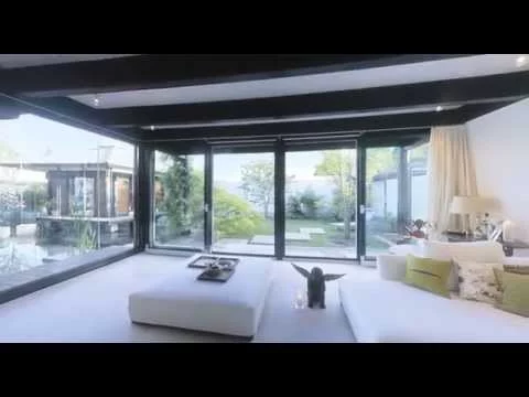 Haus mit Höfen: Wohnzimmer mit weißen Sofas und Glasfront zum Garten