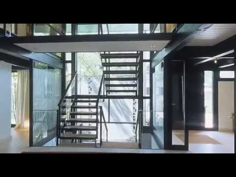 Haus mit Höfen: Halle mit offener Stahltreppe und Glaswänden