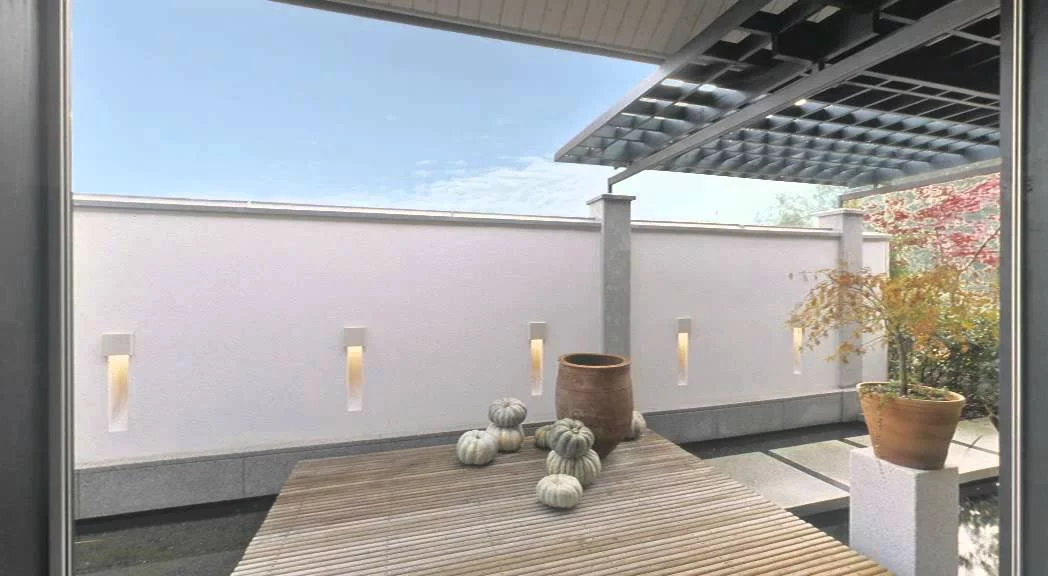 Haus am See: Freisitz mit Holzdeck vor gestalteter Grenzwand