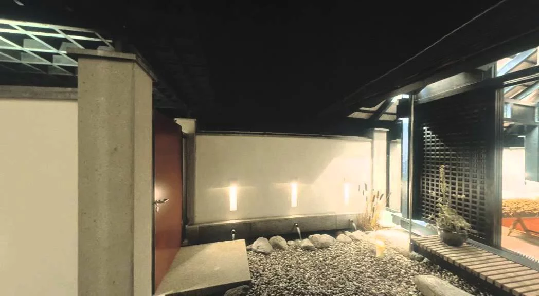 Haus am See: Eingangshof mit Pavillon und beleuchteter Grenzwand bei Nacht