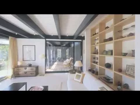 Haus mit Höfen: Wohnzimmer mit Regalwand und Blick in den Garten