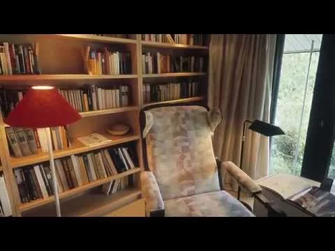 Haus mit Höfen: Bibliothek mit Bücherregalen, Lesesessel und roter Stehleuchte