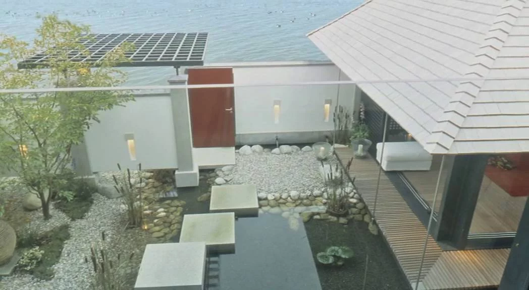 Haus am See: Blick von oben auf Eingangshof mit Trittsteinen und See